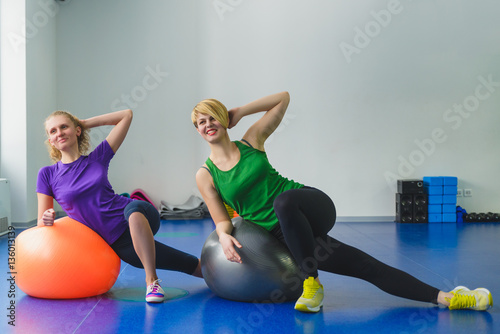 Two young sporty women doing gymnastic exercises or exercising in fitness class