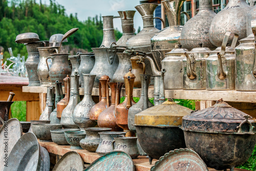 Vintage copper and brass metal pitchers, jugs, trays and other different antique handicraft household ware of ancient Caucasian folks put outdoors in a row for sale