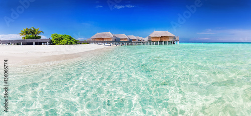 Panorama of wide sandy beach with water villas on a tropical island