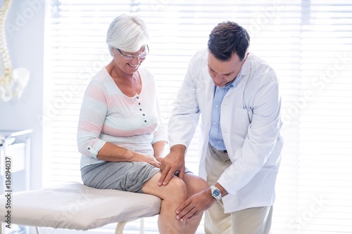 Physiotherapist giving knee therapy to senior woman