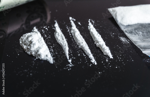 Cocaine drug addiction. Lines of cocaine on black background closeup