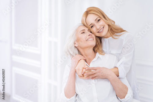 Posditive woman and her adult daughter resting at home