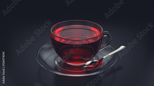 Glass cup of tea with spoon and saucer on dark background