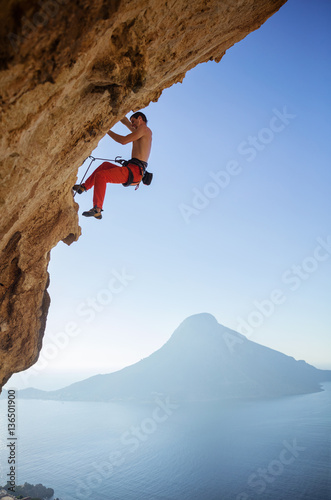 Young man climbing on overhanging cliff