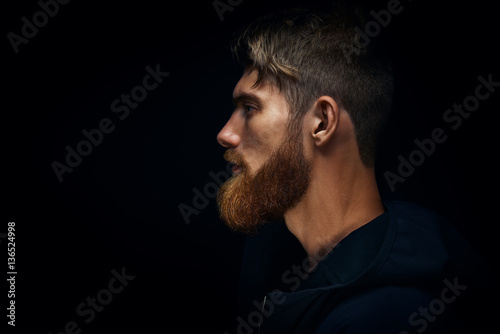 Close-up image of serious brutal bearded man on dark background