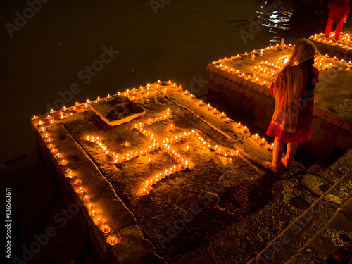 A woman stands next to swastika decoration of clay lamps (diya) in Varanasi (India) on the festival of Dev Diwali