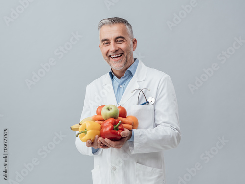 Smiling nutritionist holding fresh vegetables and fruit