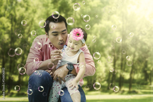 Father blowing bubble soap with his daughter