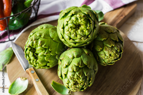 Fresh green artichokes on cutting board with peeled off leaves,