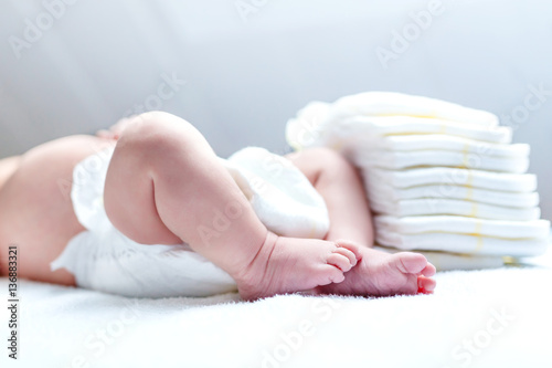 Feet of newborn baby on changing table with diapers