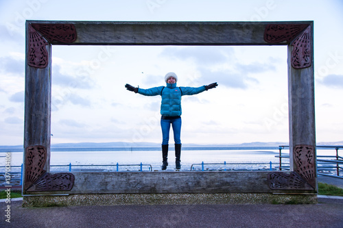 Model in big picture frame at Morecambe seafront jumping and having fun