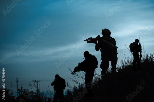 Silhouette of military soldier or officer with weapons at night. shot, holding gun