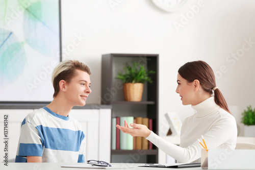 Young female psychologist working with teenager boy in office