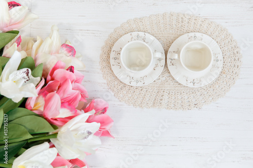 Two cup and fresh tulips on wooden table, top view.