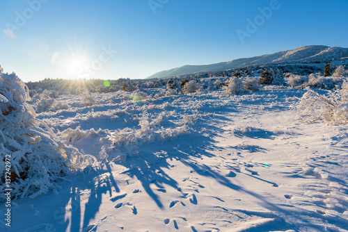 Winter amazing sunset shines on snow covered field with mountain