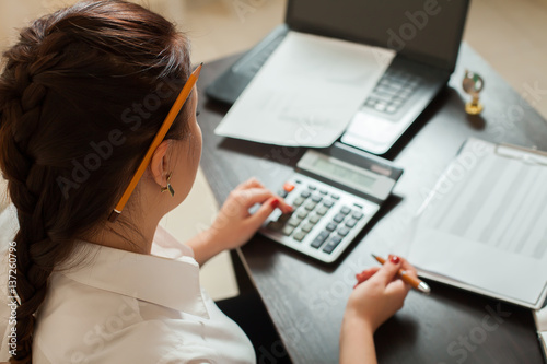 Young female bookkeeper considers on calculator