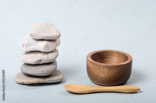 A stacked Zen stones with a wooden little spoon and a wooden little bowl.