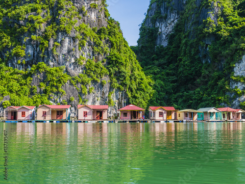 Floating fishing village reflected in emerald waters of Ha Long bay, Vietnam 