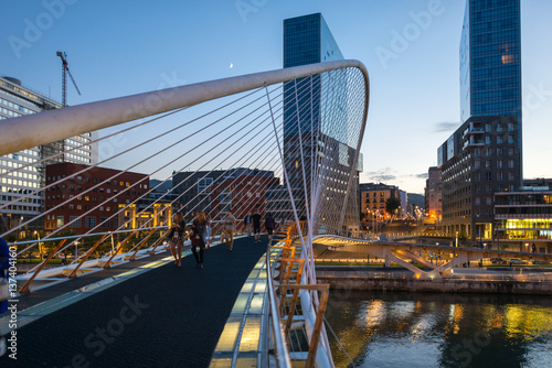 View to the Plaza de la Convivencia with the famous bridge Puente Zubizuri, The white bridge, also named Campo Volantin Bridge, is a tied arch footbridge across the Nervion River in Bilbao, Spain