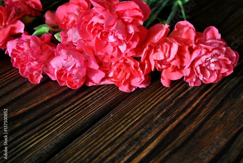 Różowe goździki na tle rustykalnych desek 