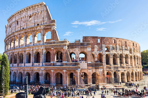 Ruins of the colosseum in Rome, walking visitors and tourists, sunny day with blue sky, Italy