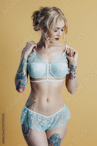 A beautiful blondie girl in a sky blue lingerie on a yellow background