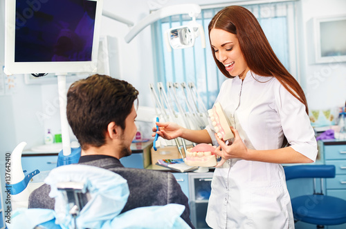 Professional woman dentist doctor working . man at dental clinic. man at dentist taking care of teeth.Dental care for people. Dentist holding dental device for fixing teeth. 