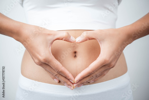 Close up of woman's hands made heart on belly isolated on white background.health care concept.