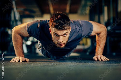 Handsome man doing pushups in the gym