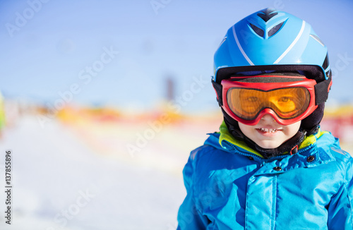 Cheerful young skier wearing safety helmet and goggles