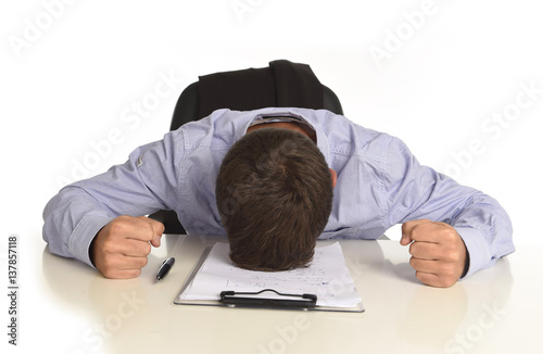 businessman sitting at office desk with hands on his head crying devastated and frustrated