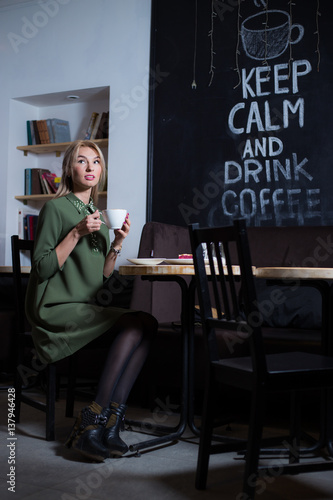 beautiful girl is drinking coffee in a cafe, girl waiting for her boyfriend on Valentine's Day
