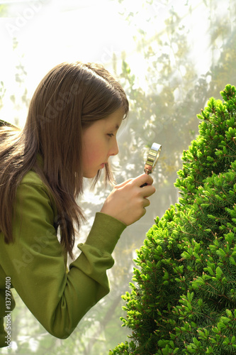 Girl looks through a magnifying glass plant