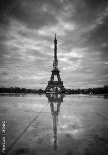 View of the Eiffel Tower from the Trocadero. Reflection tower in wet rain stone pavement. BW photography. France. Paris.