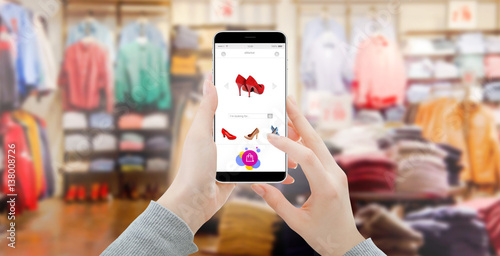 Close up of modern smartphone with shopping interface, blurred clothing store in background