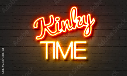 Kinky time neon sign on brick wall background.