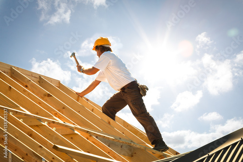 roofer or Carpenter working on Roof on construction site backlit