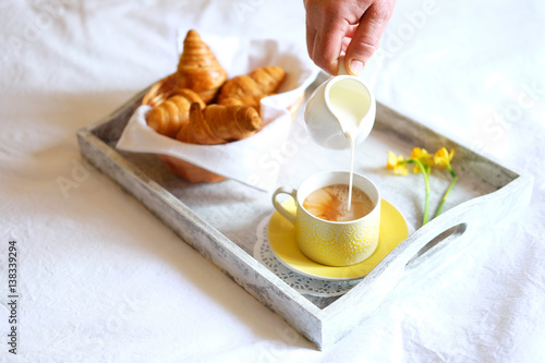 Breakfast in bed. Gray wooden tray with croissants and tea.