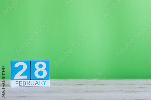 February 28th. Cube calendar for february 28 on wooden desk with green background and empty space For text. Not Leap year or intercalary day