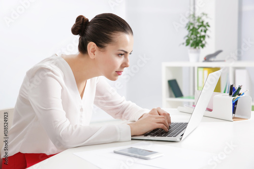 Incorrect posture concept. Young woman sitting at table in modern room