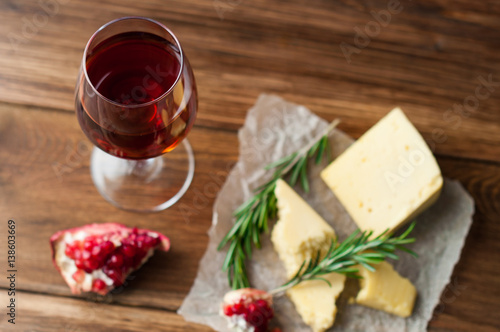 Cup with red wine, cheese and fruit on the table. Pomegranates on a dark background. Banner for restaurant