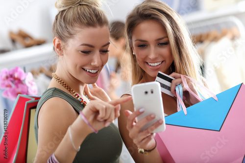 Happy friends shopping in store with smartphone