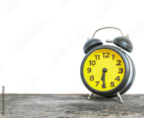 Closeup black and yellow alarm clock for decorate show half past six or 6:30 a.m. on old brown wood desk isolated on white background with copy space