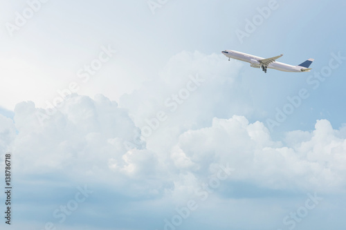 Commercial airplane departure from airport flying over bright blue sky and white clouds on sky