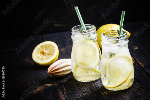 Iced lemonade with juice in the bottles, dark background, selective focus