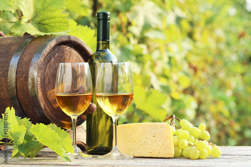Wine in glasses with bunch of grape and cheese on wooden table