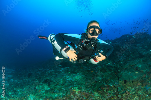 Female SCUBA diver using a techical side mount system on a deep coral reef