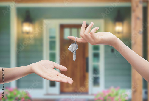 Mani con chiavi con sfondo porta di casa