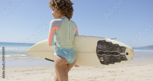 Female holding white surfboard walking to sea to surf. Back view. Tarifa beach. Provincia Cadiz. Spain. 