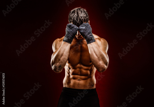 Strong muscular fighter hiding face from camera